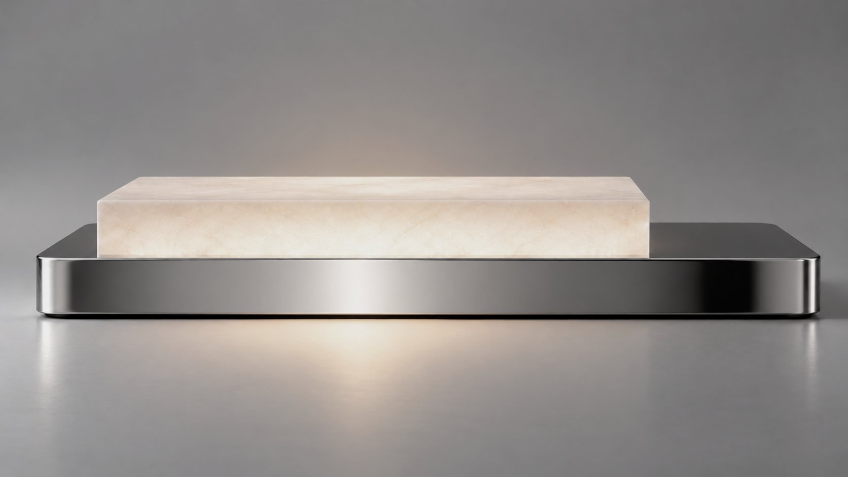 A low table light seen side-on: a glowing alabaster block resting on a polished aluminium base against a grey wall.