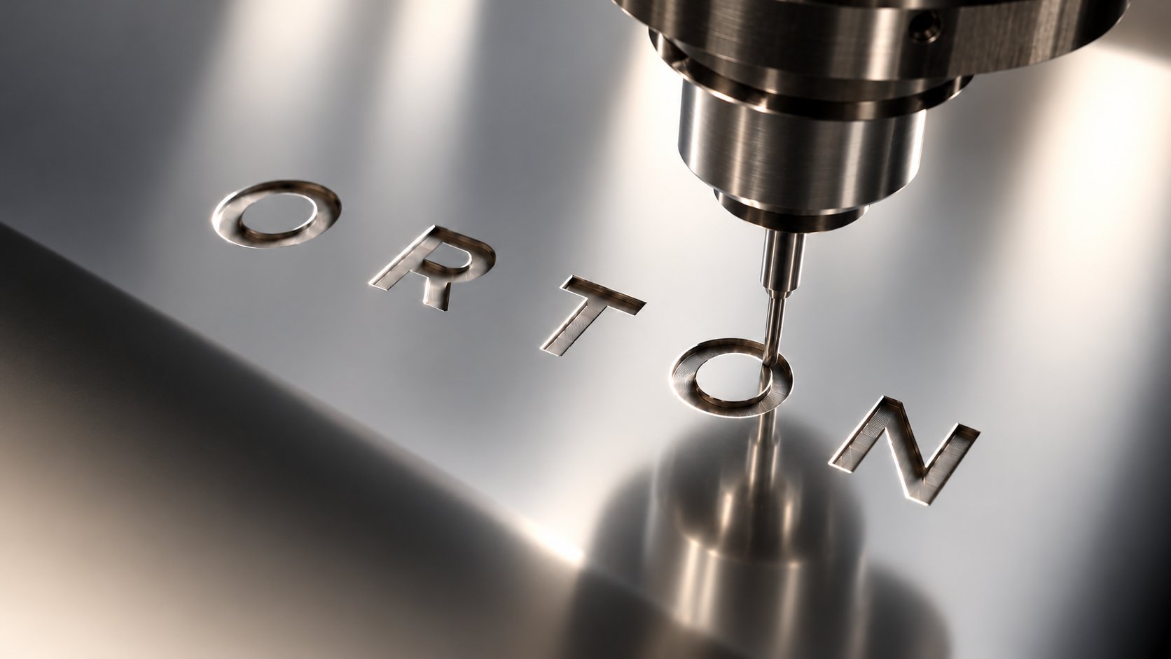 A milling cutter engraving the ORTON wordmark into a polished metal sheet.